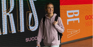 a woman walking down a hallway with a backpack