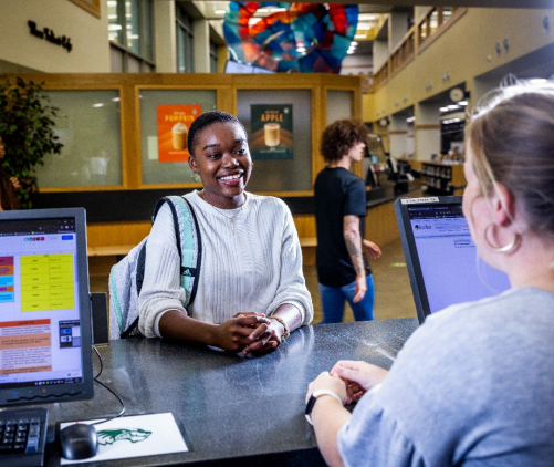 A library aide helps a UVU student at the Circulation Desk