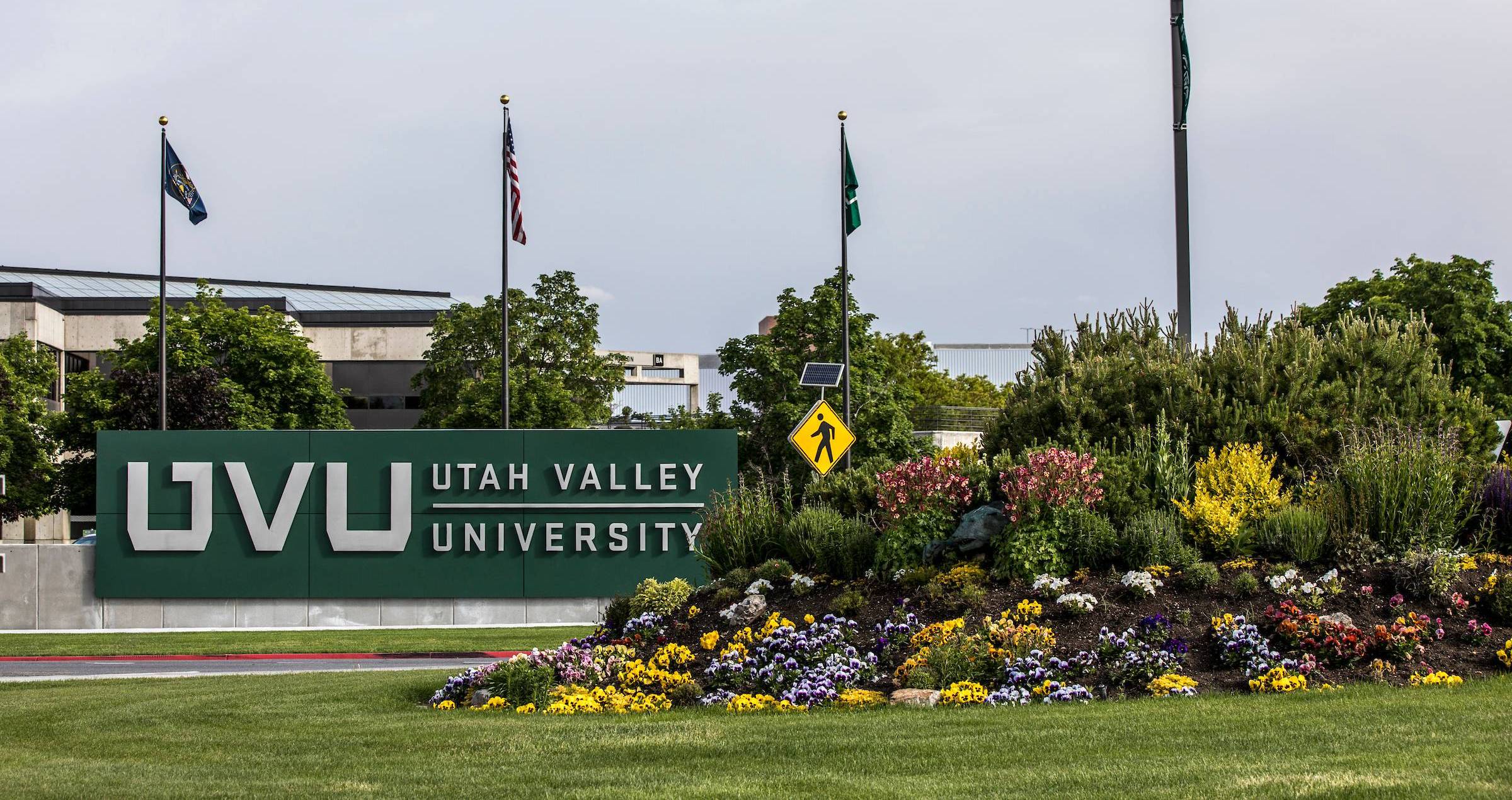 Image of the UVU signage in front of the Orem campus, with a flower patch right beside it