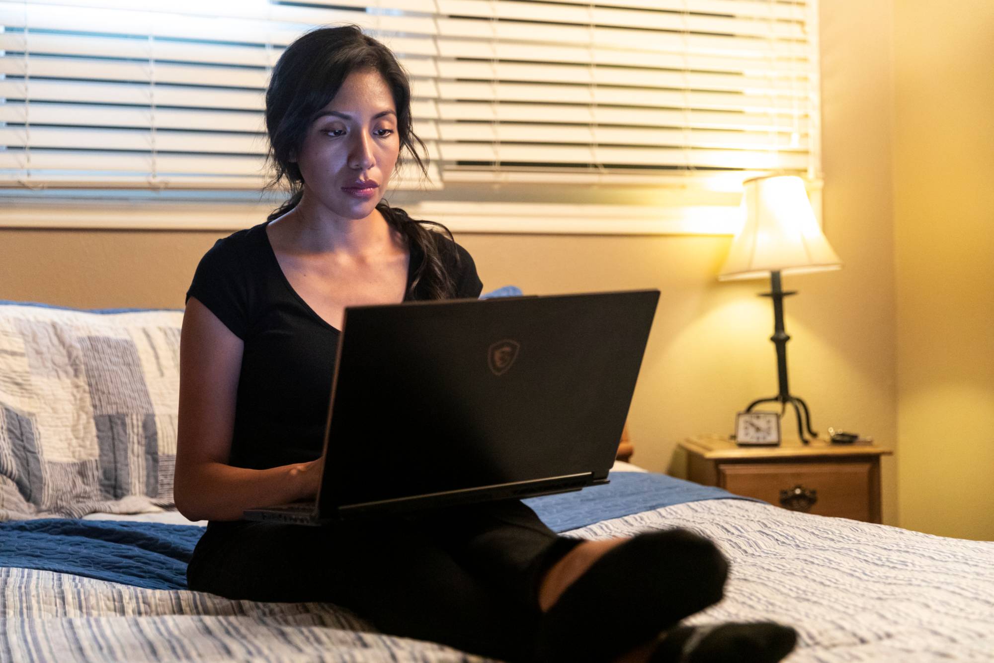 image of a person typing on a laptop in their bedroom