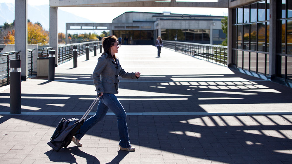 student walking with suitcase