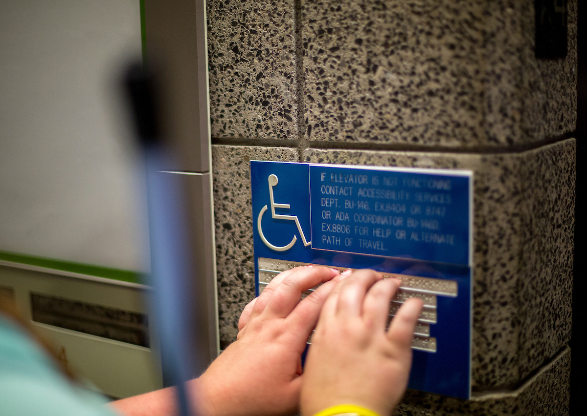 Image of a student reading a braille classroom sign