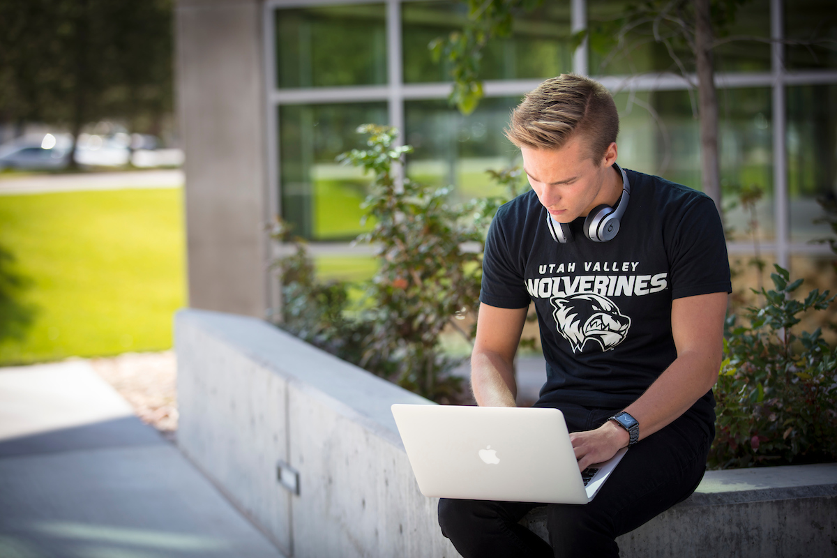 student in the UVU courtyard using a laptop