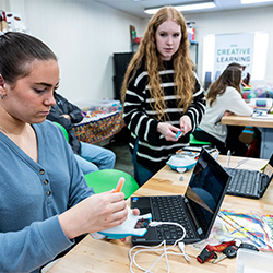 students at a desk with laptops