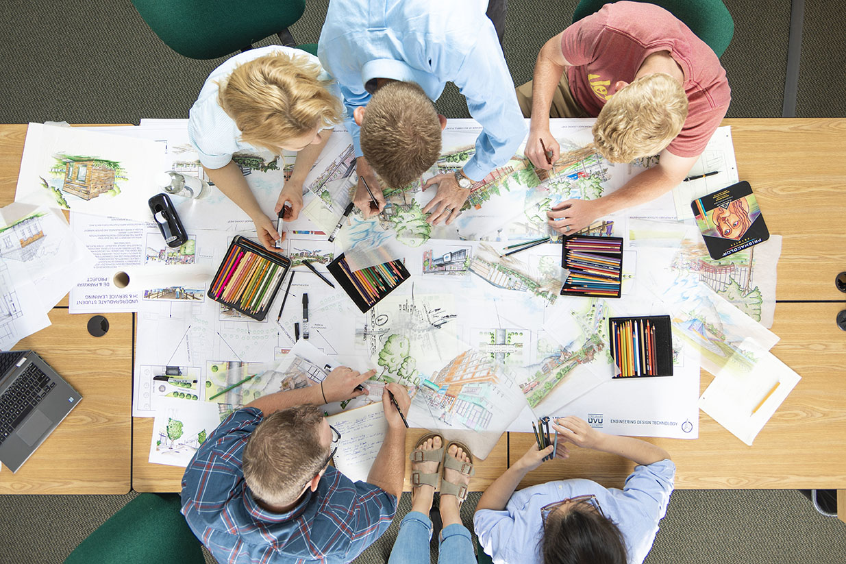 Overhead shot of architecture students drafting designs at a table