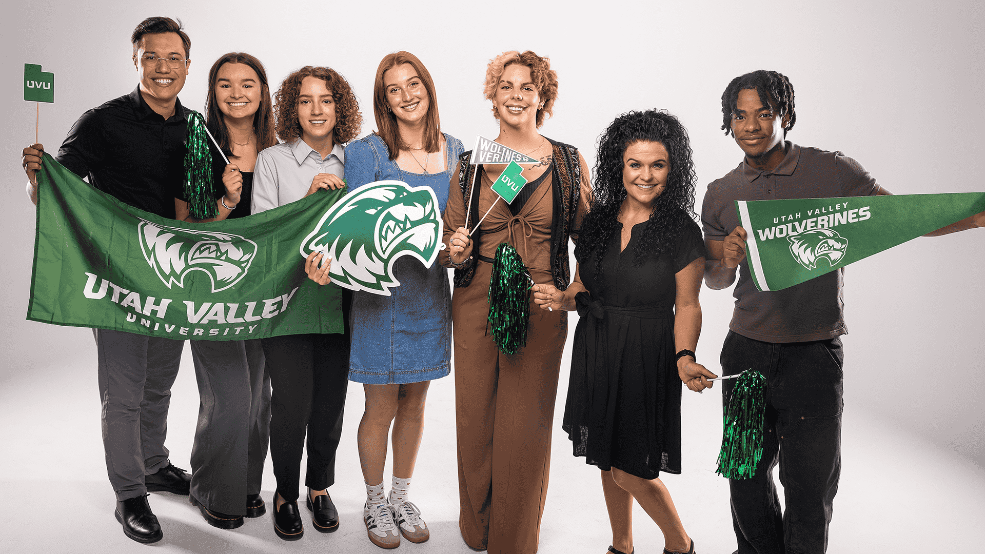 2024-25 Student Alumni Ambassadors smile and post with a UVU flag and pompoms.