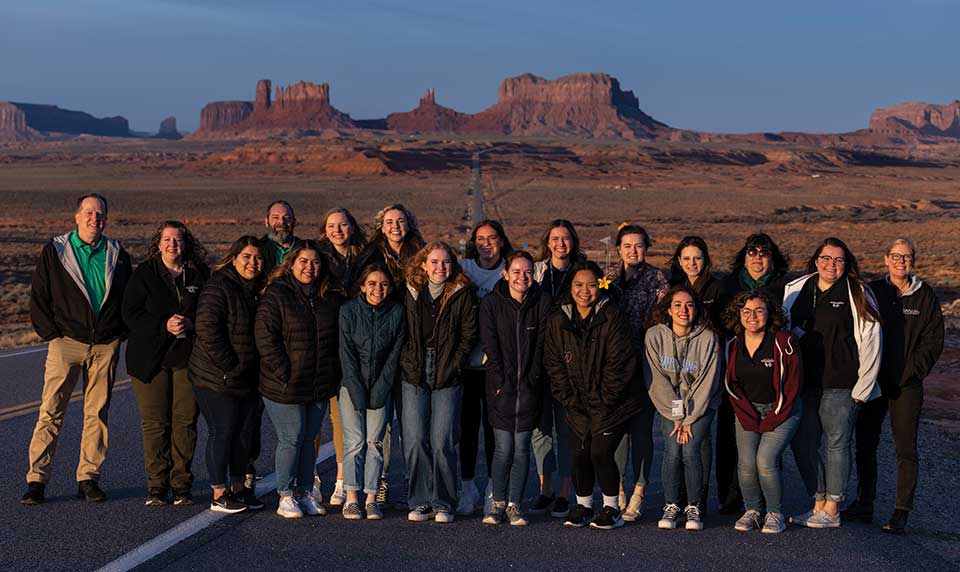 A group of UVU School of Education students and faculty members pose in front of rock formations in Monument Valley in Utah. 