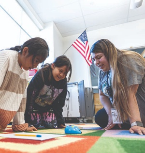 A UVU School of Education student works with two young girls from a Navajo Nation elementary school using a robotic mouse as a teaching tool. 