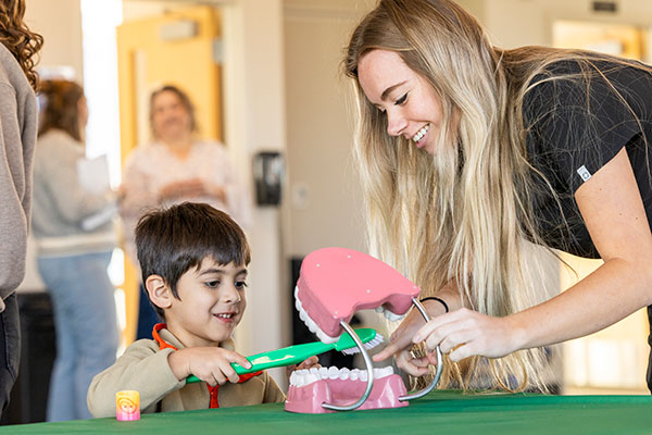 Image of a student and child learning with a mouth model