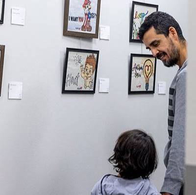 MNCA Art show, a dad and his son looking at some art