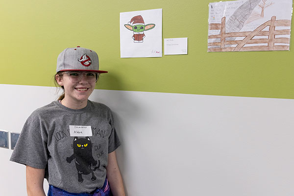 Image of a kid at a event by some artwork on the wall