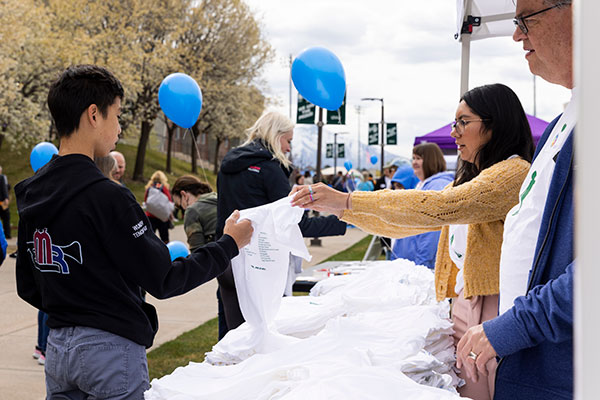 People at a booth handing out shirts to people at an event