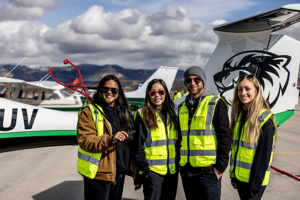 Four aviation students posing in front of UVU branded plane