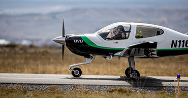 UVU branded plane about to take off. Pilot inside plane is waving