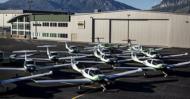 several planes parked in formation in front of a hangar