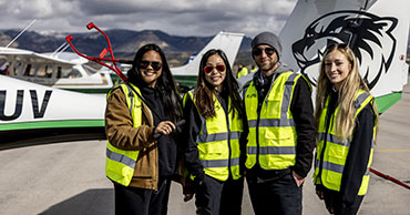 four people in high vis vests in front of a plane