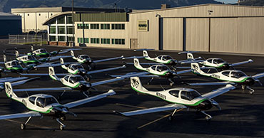 several planes parked in formation in front of a hangar