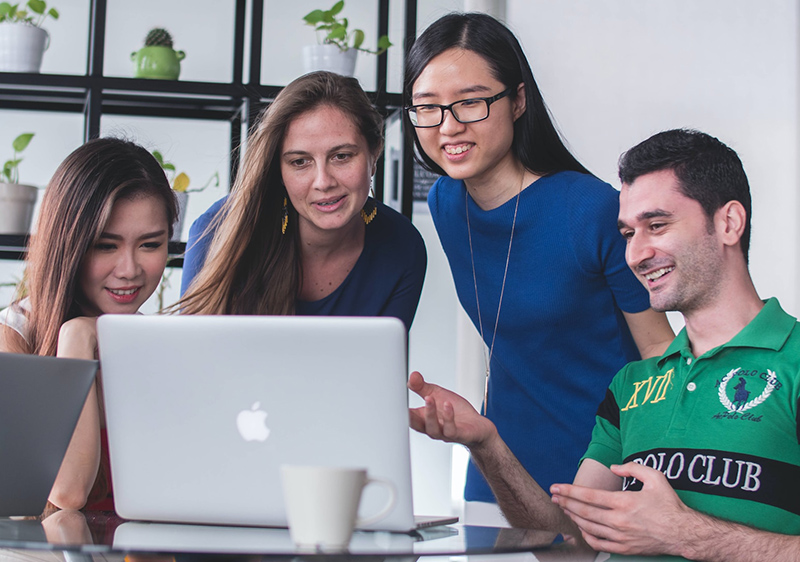 4 students looking at a laptop screen