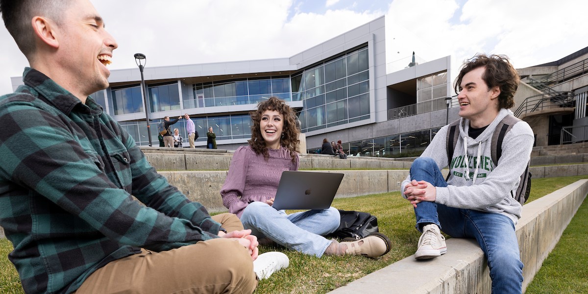 students sitting outside the UVU campus with their laptops out