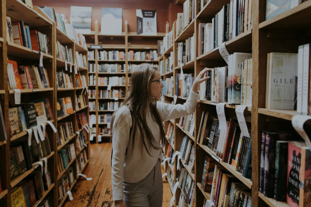 person looking through books at a library