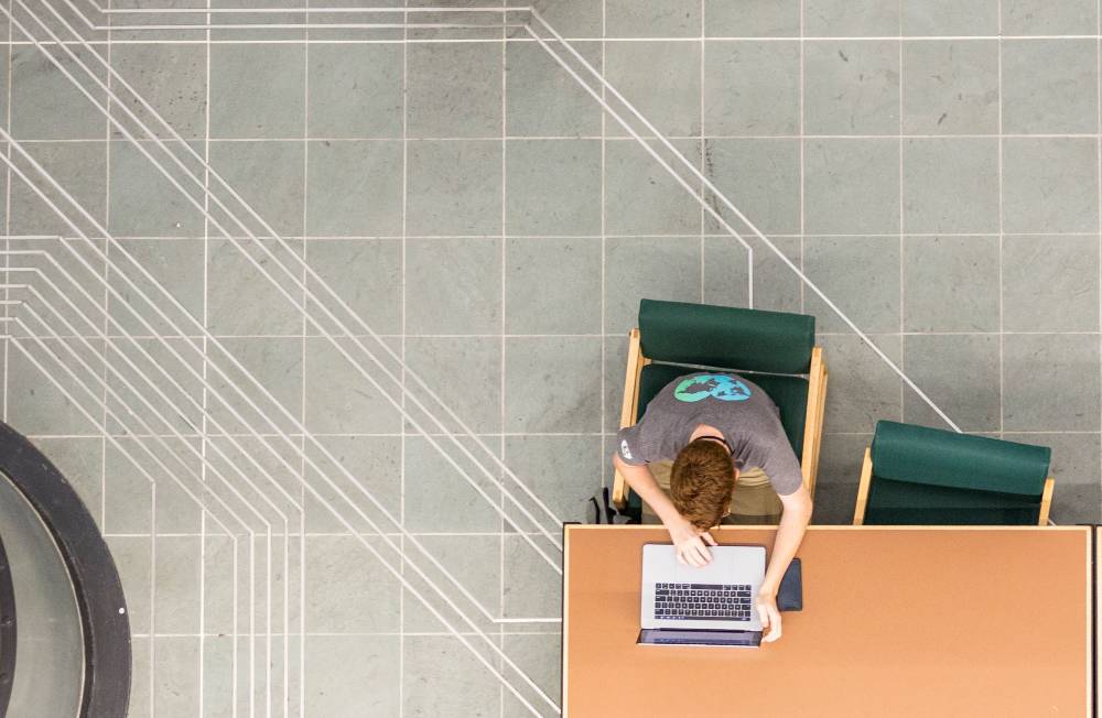Overhead view of student studying on laptop in a room with geometric concrete designs.