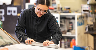 student sanding a car hood