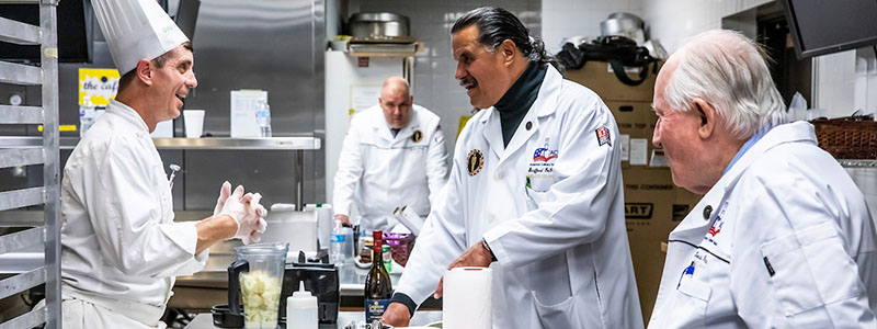 three chefs cooking in a kitchen