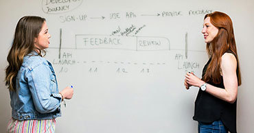 two women standing at a whiteboard