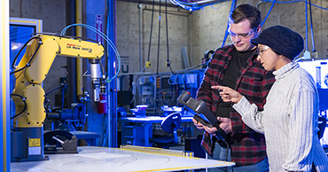 two students using a robotics machine