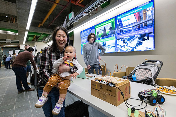 CET Expo attendee holding baby in front of project display