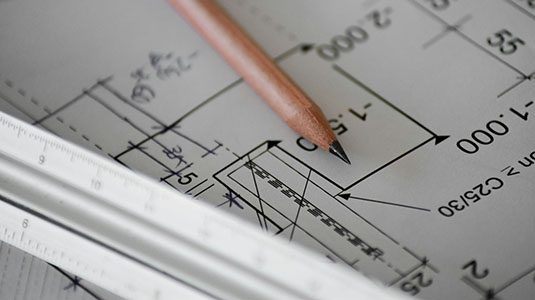 close up of a pencil, ruler, and blueprint