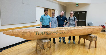 group of students posed with a large canoe