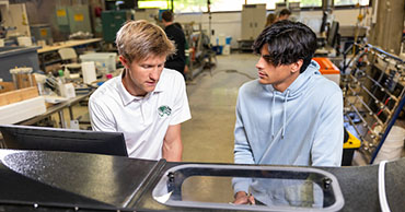 a student and a professor working on a machine