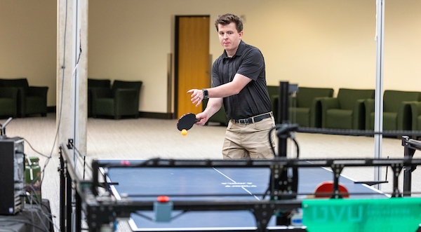 man playing ping pong against a robot