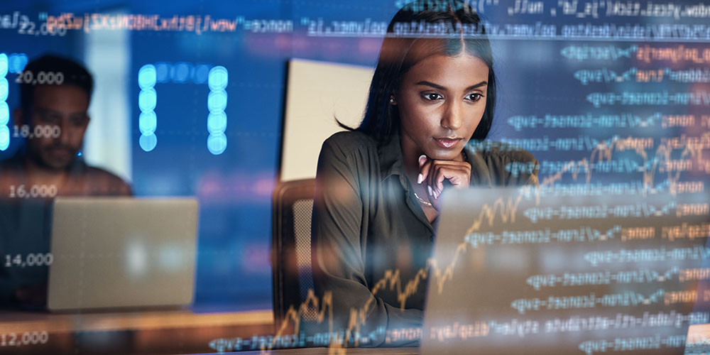 woman using a laptop with code floating in front