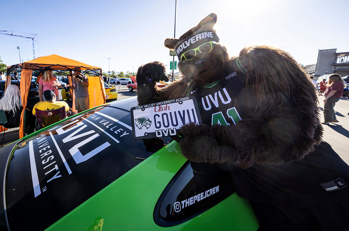 Willy the Wolverine posing in front of UVU branded car