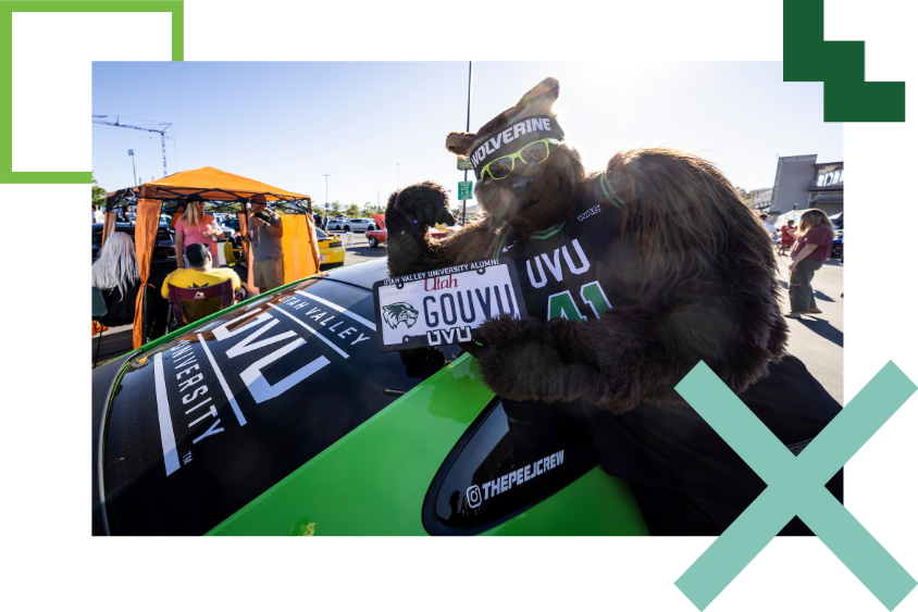 Willy the Wolverine posing in front of UVU branded car