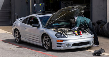 student working on a car engine