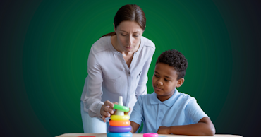 woman helping a child put a green ring on a stack of rings