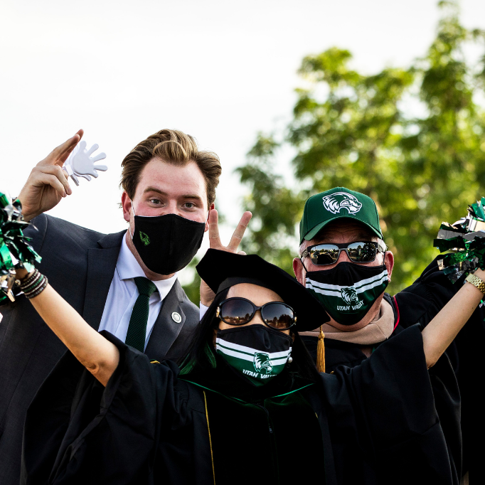 trio of individuals wearing masks, arms outstretched
