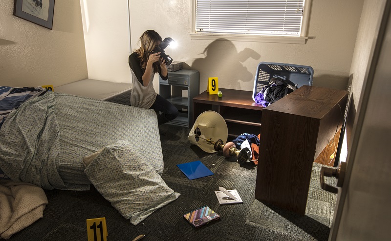 woman holding a camera taking a picture of a forensic area