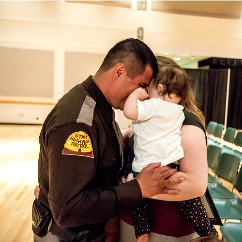 A man holding a child while wearing a state trooper uniform