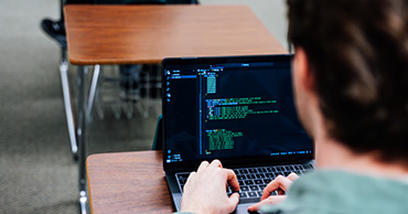 man writing code on a laptop