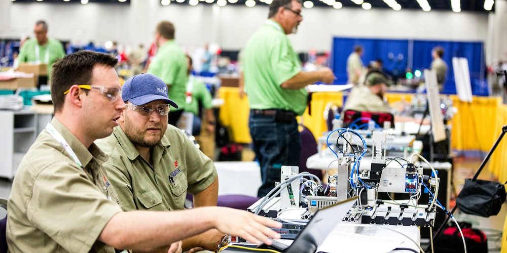 two men sitting at a table with electronics on it