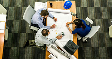 overhead shot of three people working at a desk