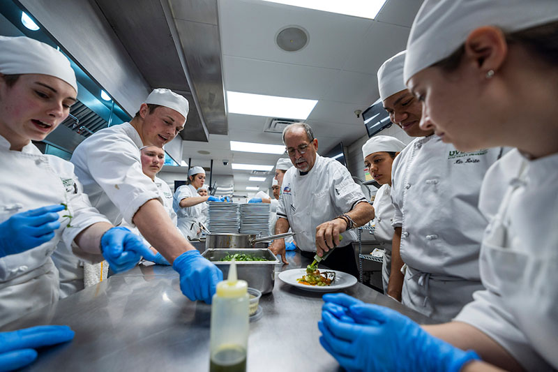 Culinary Arts students surrounding a table preparing dishes