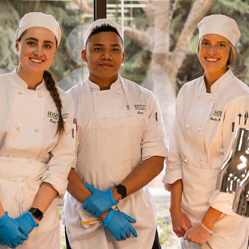 three students in chef uniforms