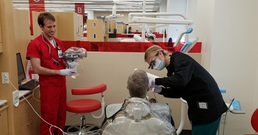 A UVU dental student and a U of U dental student work on a patient 