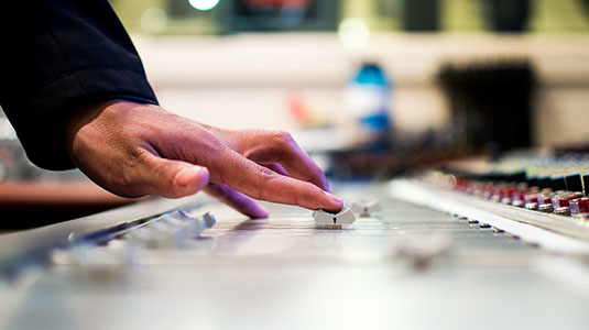 hand on an audio mixing board