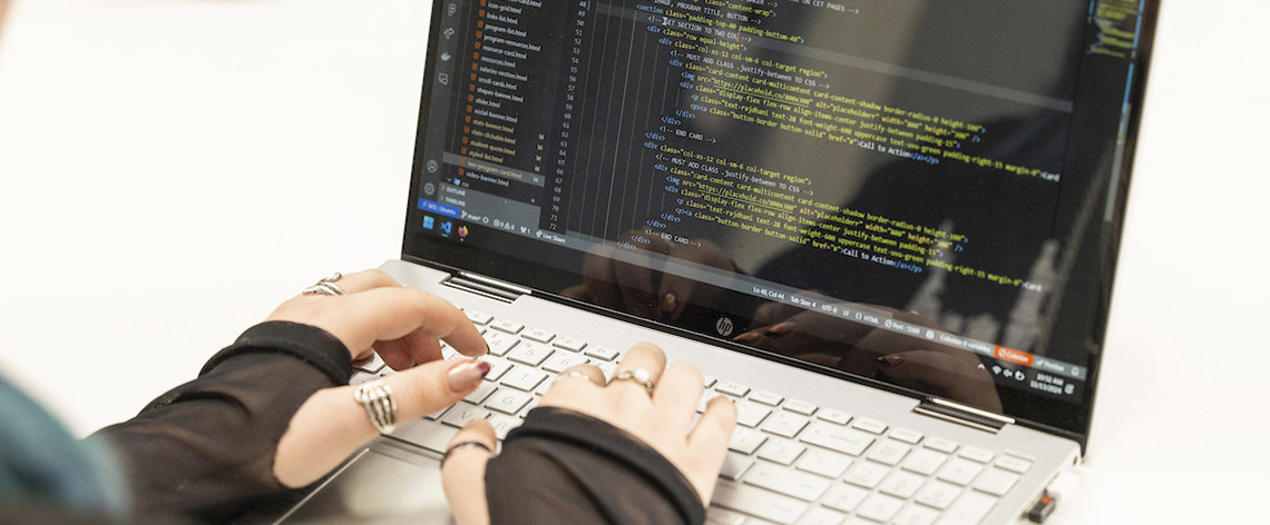 close up of person's hands coding on laptop